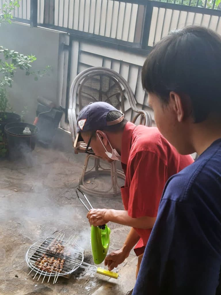 My dad and I cooking satay on a small makeshift grill